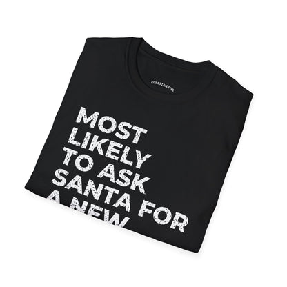 Folded black t-shirt printed with "MOST LIKELY TO ASK SANTA FOR A NEW TRAINER" in white