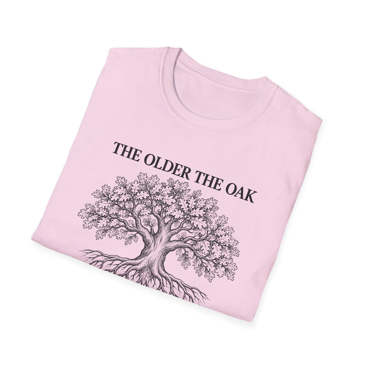 Folded light pink t-shirt printed with "THE OLDER THE OAK, THE STRONGER IT STANDS" in black, with a drawing of an oak tree and its roots