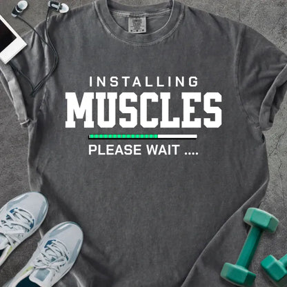 Pepper t-shirt printed with "Installing Muscles Please Wait ...." in white and multicolor, with a loading bar