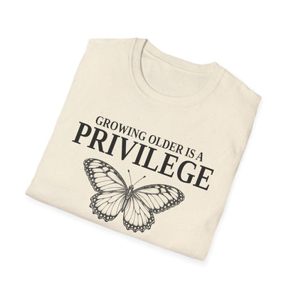 Folded natural t-shirt printed with "GROWING OLDER IS A PRIVILEGE, GROWING STRONGER IS A CHOICE" in black, with a line-drawn butterfly