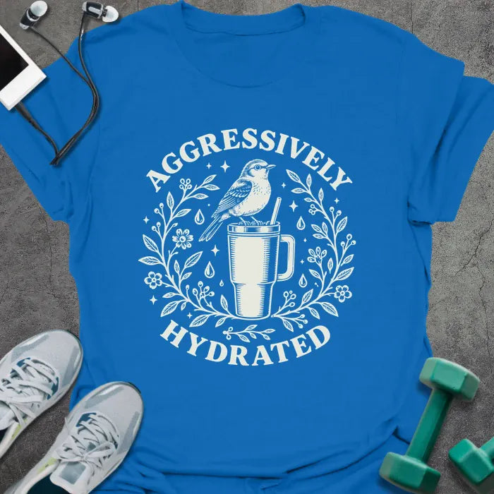Royal blue t-shirt printed with "AGGRESSIVELY HYDRATED" in cream, with a bird perched on a big insulated tumbler inside a wreath of leaves, flowers and water drops