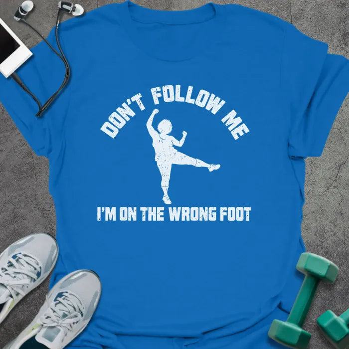 Royal blue t-shirt printed with "DON'T FOLLOW ME, I'M ON THE WRONG FOOT" in white, with an older woman doing an aerobics kick