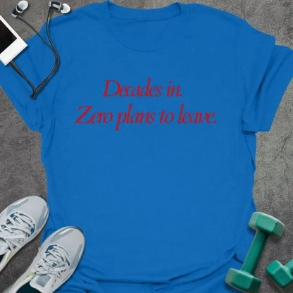 Royal blue t-shirt printed with "Decades in. Zero plans to leave." in red