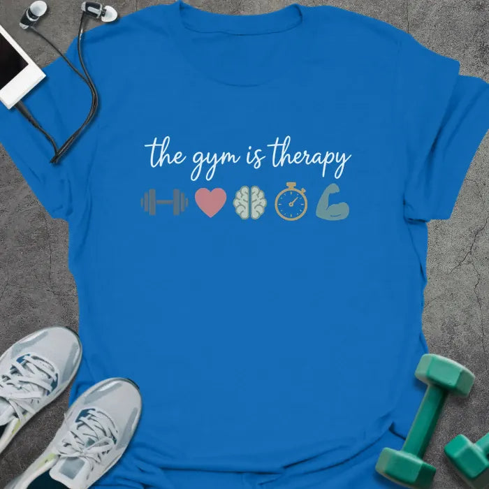Royal blue t-shirt printed with "the gym is therapy" in gray, pink, gray, gold, and green, with a dumbbell, heart, brain, stopwatch, and bicep emoji
