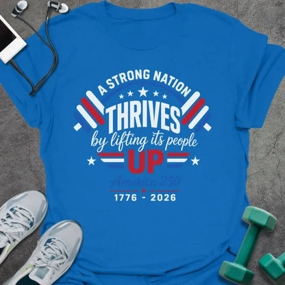 Royal blue t-shirt printed with "A STRONG NATION THRIVES by lifting its people UP" in red and white, with barbells and stars in American flag style
