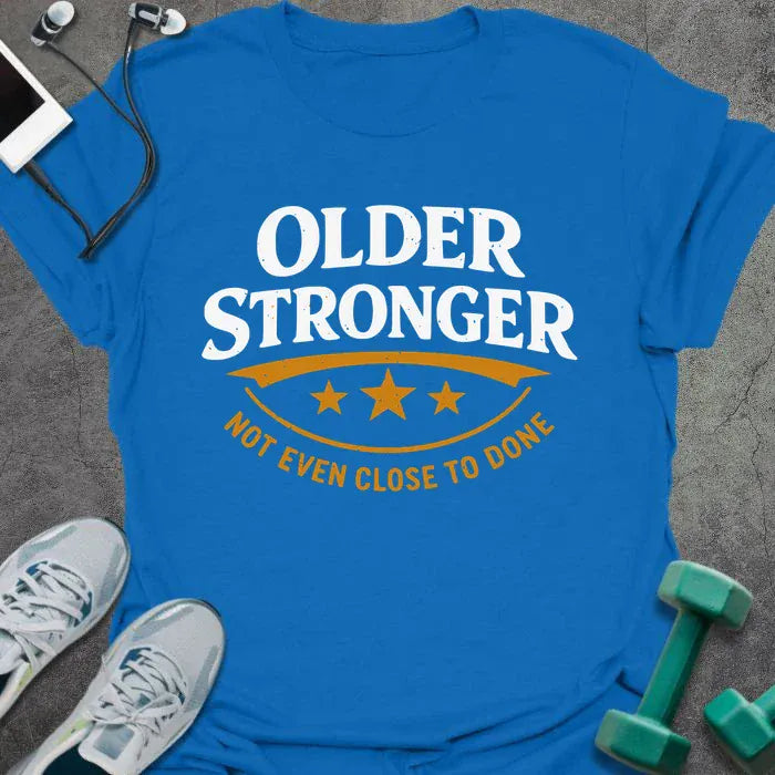 Royal blue t-shirt printed with "Older Stronger Not Even Close to Done" in white and orange, with a scoreboard showing three stars