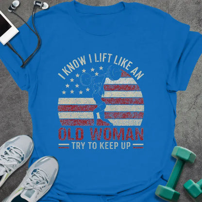 Royal blue t-shirt printed with "I Know I Lift Like an Old Woman Try to Keep Up" in red and white, with a flexing woman silhouette and American flag kettlebell