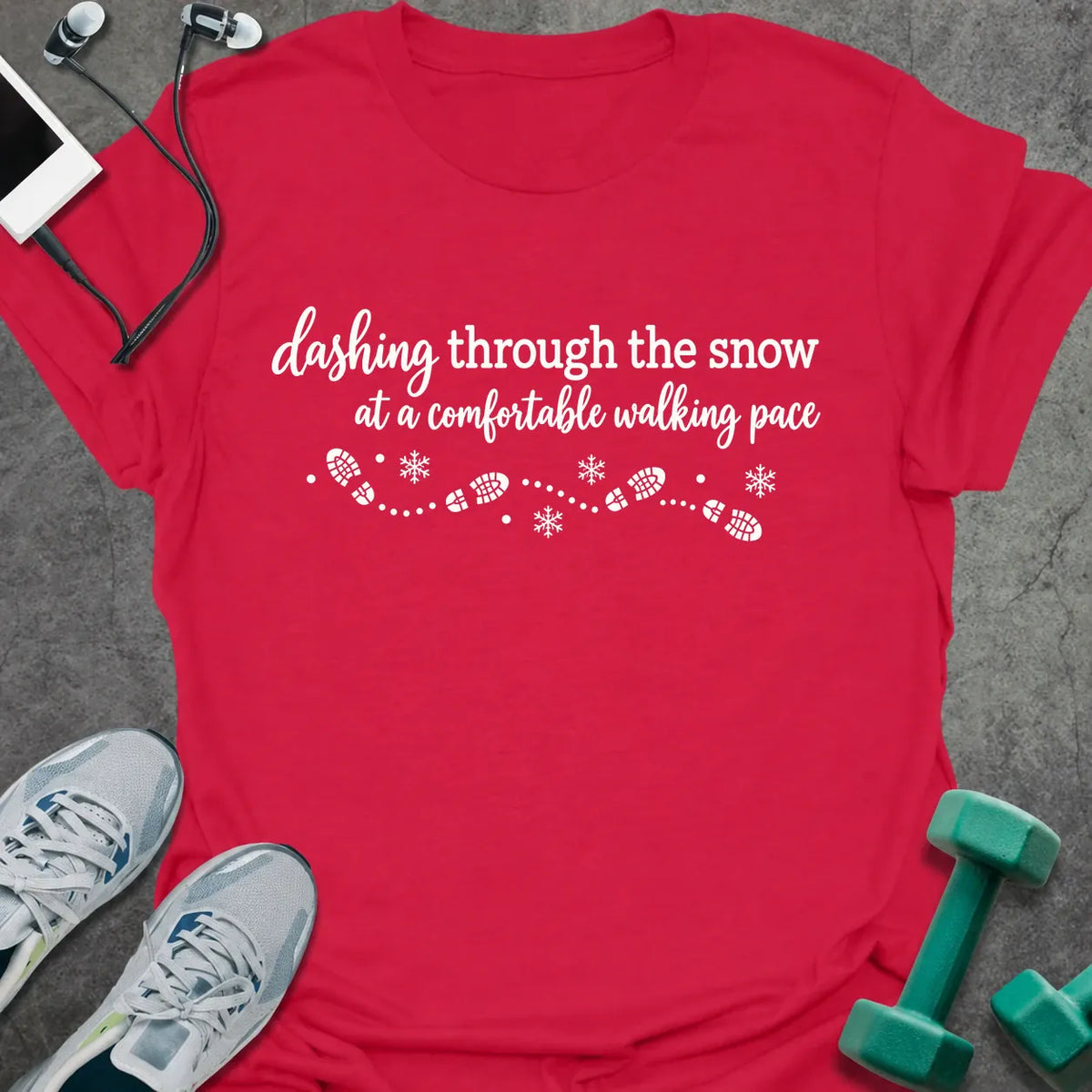 Cherry red t-shirt printed with "dashing through the snow at a comfortable walking pace" in white, with a dotted trail of footprints and snowflakes