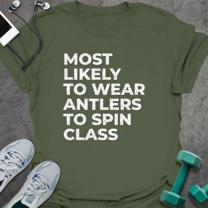 Military green t-shirt printed with "MOST LIKELY TO WEAR ANTLERS TO SPIN CLASS" in white
