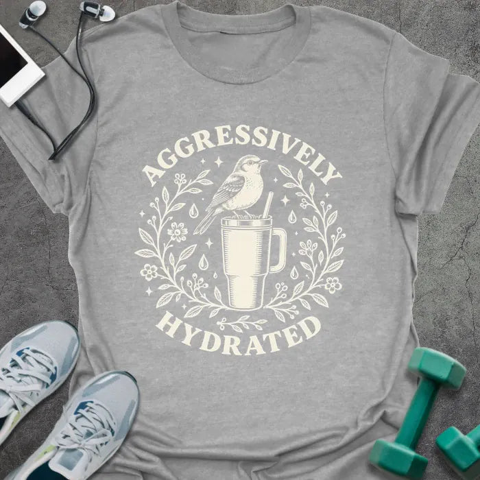 Sport grey t-shirt printed with "AGGRESSIVELY HYDRATED" in cream, with a bird perched on a big insulated tumbler inside a wreath of leaves, flowers and water drops