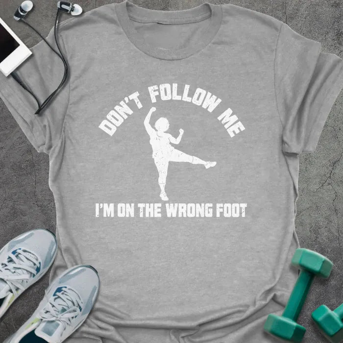 Sport grey t-shirt printed with "DON'T FOLLOW ME, I'M ON THE WRONG FOOT" in white, with an older woman doing an aerobics kick