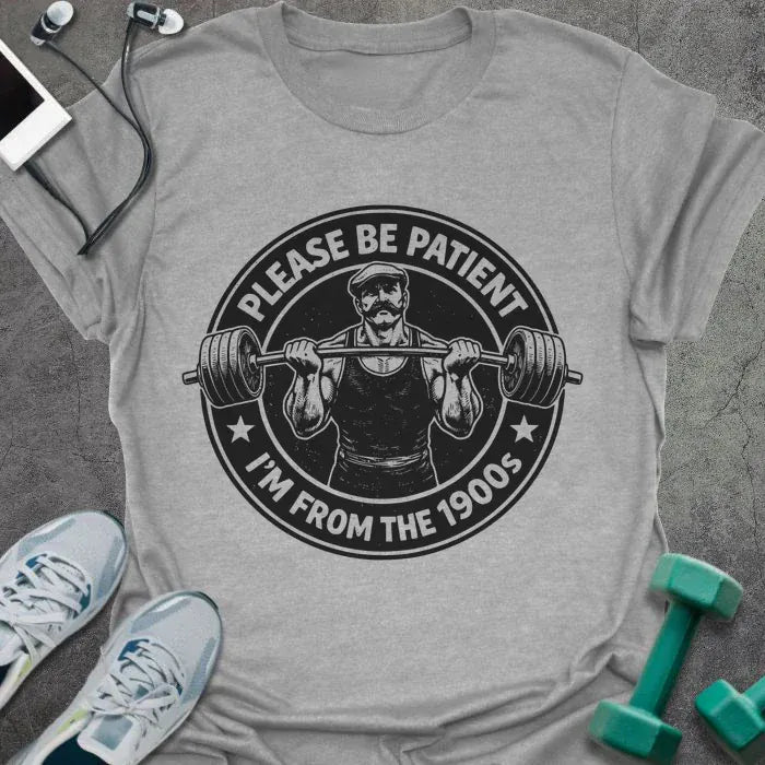 Sport grey t-shirt printed with "Please Be Patient I'm From the 1900s" in black, with a barbells and a retro strongman illustration