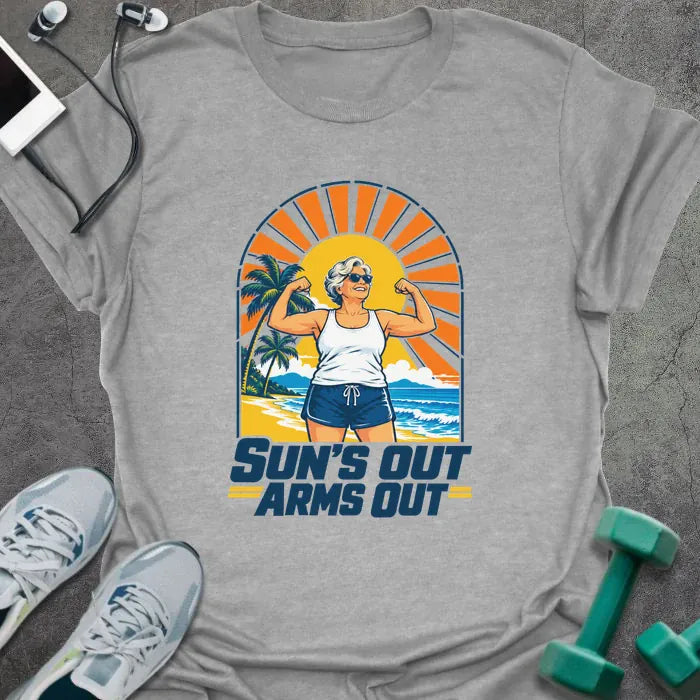 Sport grey t-shirt printed with "SUN'S OUT ARMS OUT" in navy blue, with a retro beach sunset and an older woman flexing her arms