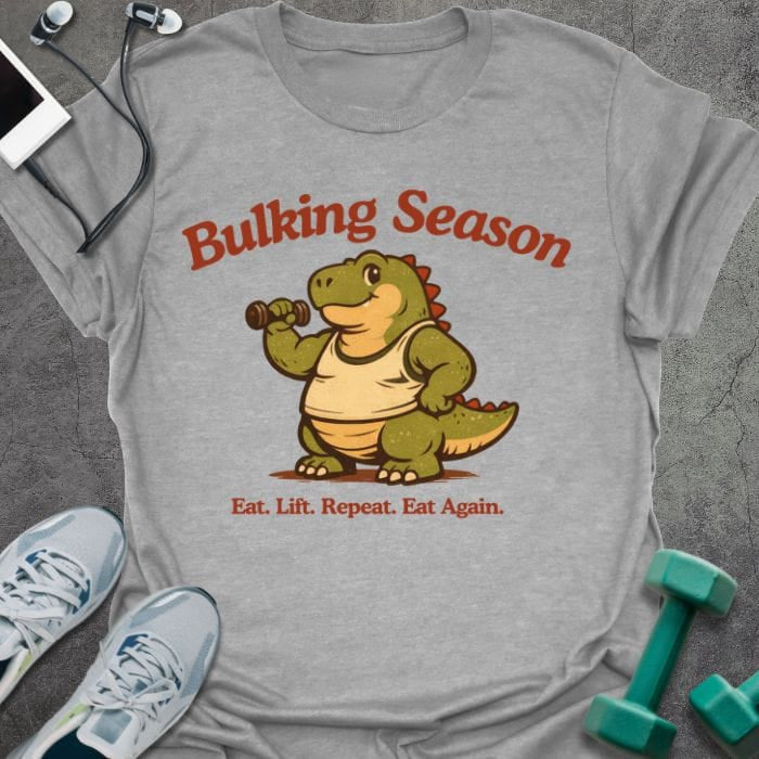 Sport grey t-shirt printed with "Bulking Season Eat. Lift. Repeat. Eat Again." in brown and green, with dinosaur lifting weights graphic