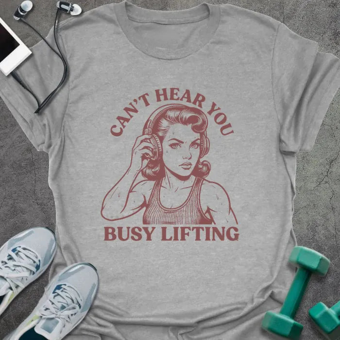 Sport grey t-shirt printed with "Can't Hear You Busy Lifting" in rust, with an illustration of a woman with headphones