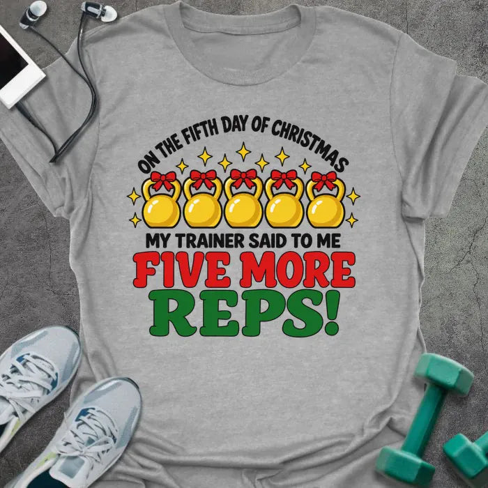 Sport grey t-shirt printed with "ON THE FIFTH DAY OF CHRISTMAS MY TRAINER SAID TO ME, FIVE MORE REPS!" in black, red and green, with five gold kettlebells tied with red bows