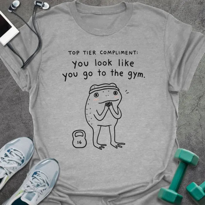 Sport Grey t-shirt printed with "TOP TIER COMPLIMENT: you look like you go to the gym." in black, with frog graphic holding barbells
