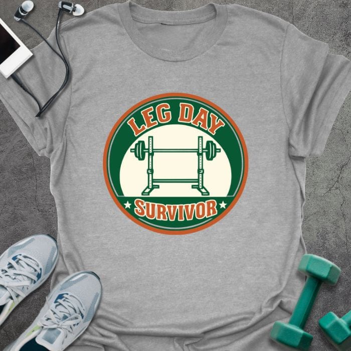 Sport grey t-shirt printed with "Leg Day Survivor" in orange and red, with barbell in circular badge