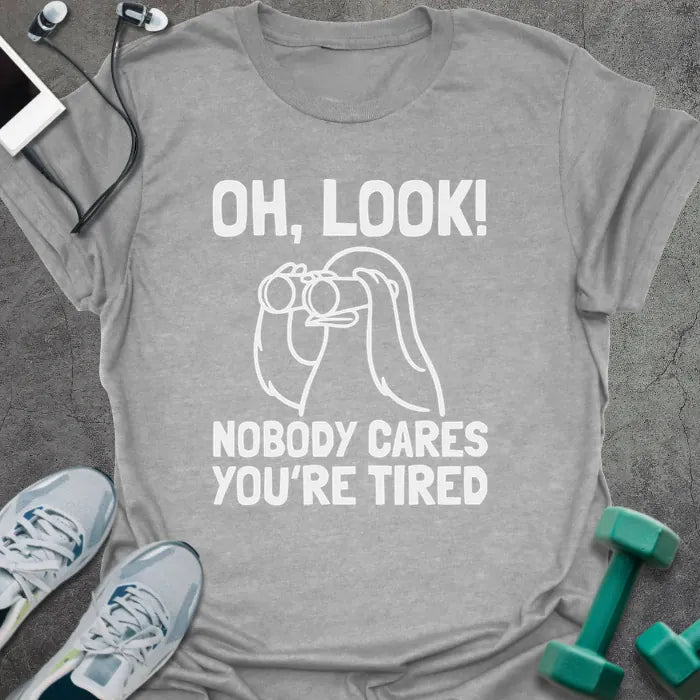 Sport grey t-shirt printed with "Oh, Look! Nobody Cares You're Tired", with an illustration of a person with binoculars