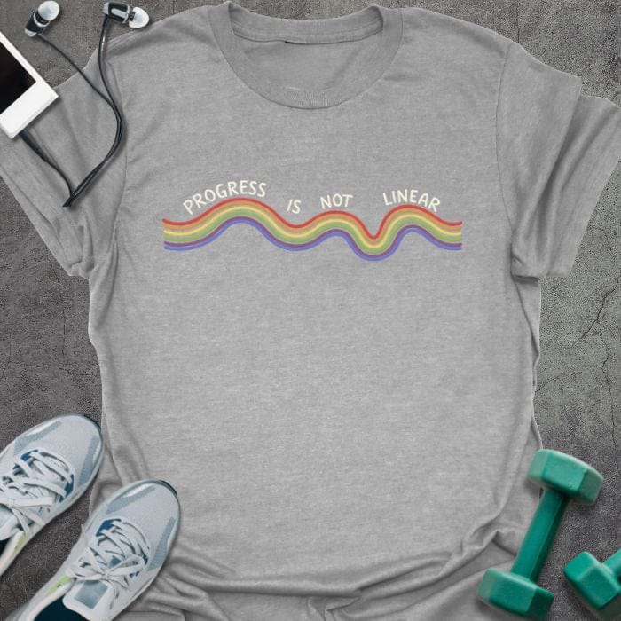 Sport grey t-shirt printed with "Progress is Not Linear" in white, rainbow, with a wavy rainbow line