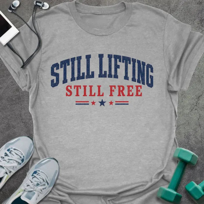 Sport grey t-shirt printed with "Still Lifting Still Free" in blue and red, with stars