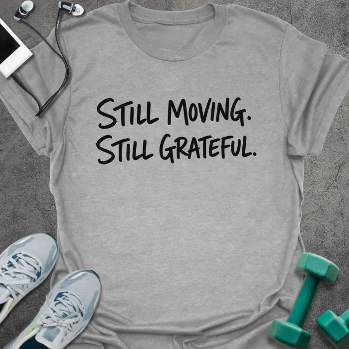 Sport Grey t-shirt printed with "Still Moving. Still Grateful." in black handwritten lettering