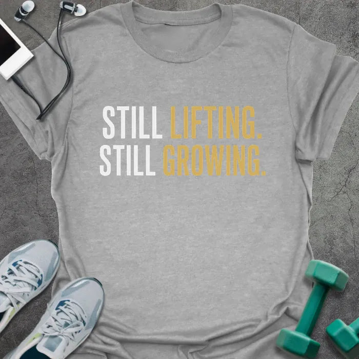 Sport grey t-shirt printed with "Still Lifting. Still Growing." in white and gold