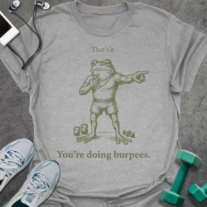 Sport grey t-shirt printed with "That's it. You're doing burpees." in tan, with an illustration of a frog character in sportswear pointing