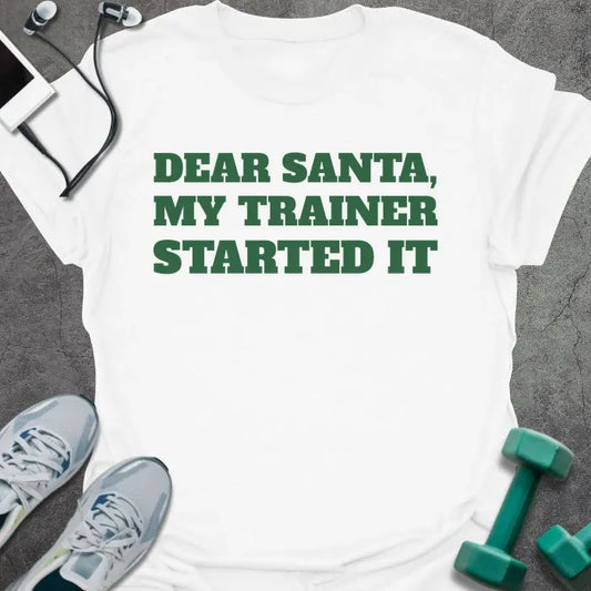 White t-shirt printed with "DEAR SANTA, MY TRAINER STARTED IT" in green
