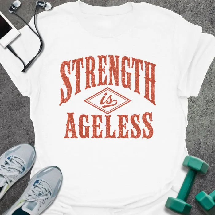 White t-shirt printed with "STRENGTH is AGELESS" in rust/terracotta weathered vintage lettering with diamond graphic