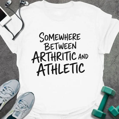 White t-shirt printed with "SOMEWHERE BETWEEN ARTHRITIC AND ATHLETIC" in black