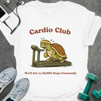 White t-shirt printed with "Cardio Club We'll Get to 10,000 Steps Eventually" in brown and red, with turtle on treadmill graphic