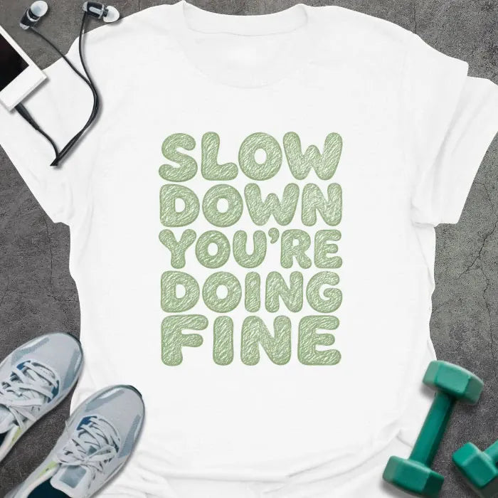 White t-shirt printed with "SLOW DOWN YOU'RE DOING FINE" in green