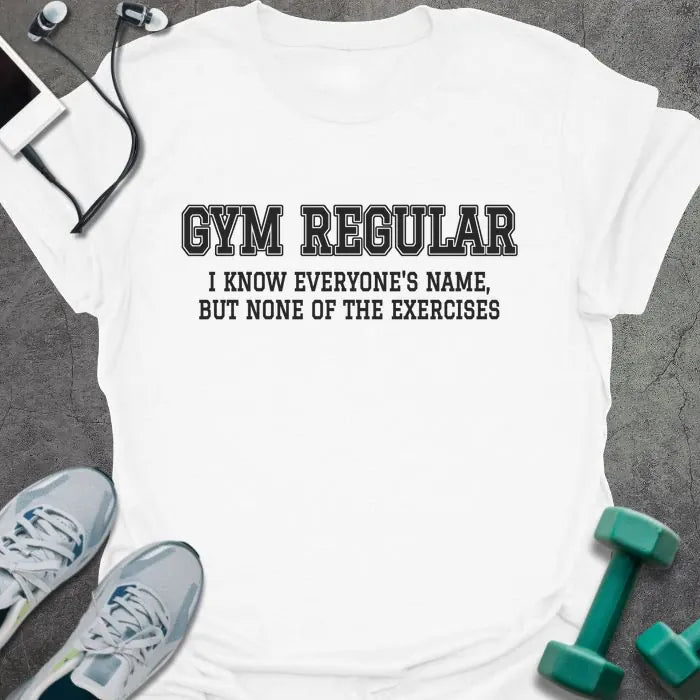 White t-shirt printed with "GYM REGULAR, I KNOW EVERYONE'S NAME, BUT NONE OF THE EXERCISES" in charcoal