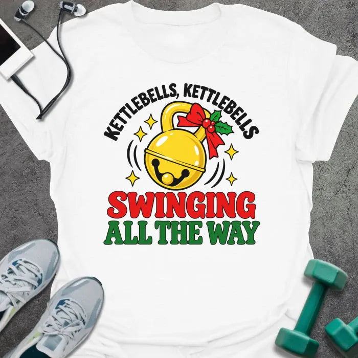 White t-shirt printed with "KETTLEBELLS, KETTLEBELLS, SWINGING ALL THE WAY" in black, red and green, with a gold jingle bell kettlebell and holly
