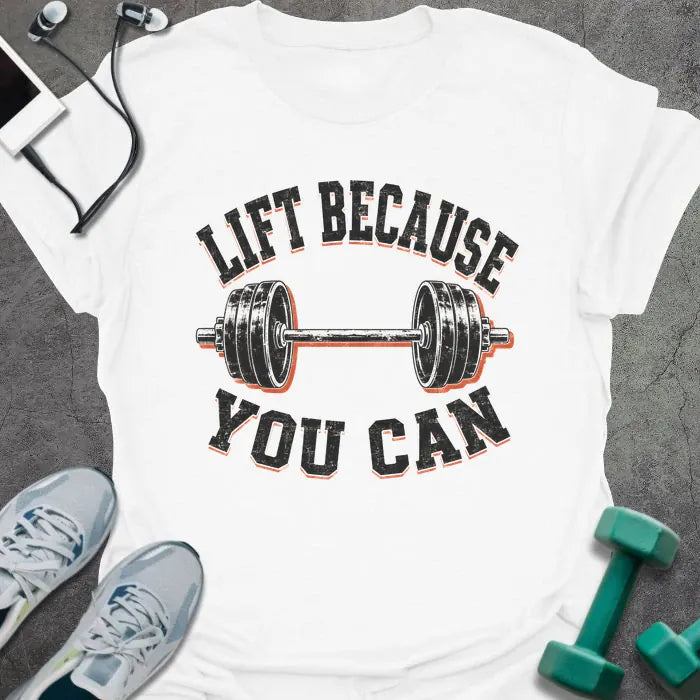 White t-shirt printed with "LIFT BECAUSE YOU CAN" in black and red text with a barbell graphic