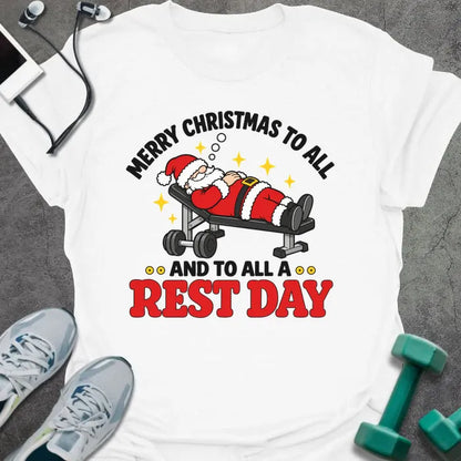 White t-shirt printed with "MERRY CHRISTMAS TO ALL AND TO ALL A REST DAY" in black and red, with Santa asleep on a weight bench
