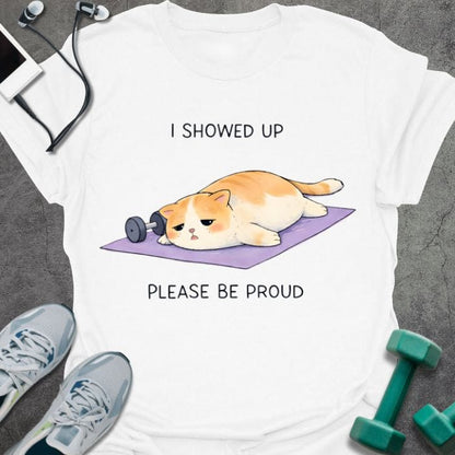 White t-shirt printed with "I Showed Up Please Be Proud" in orange, white, purple, with an orange and white cat on a purple yoga mat