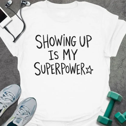 White t-shirt printed with "SHOWING UP IS MY SUPERPOWER" in black handwritten lettering, with a star outline