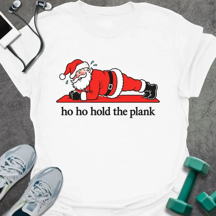 White t-shirt printed with "ho ho hold the plank" in black, with Santa holding a plank on a red mat