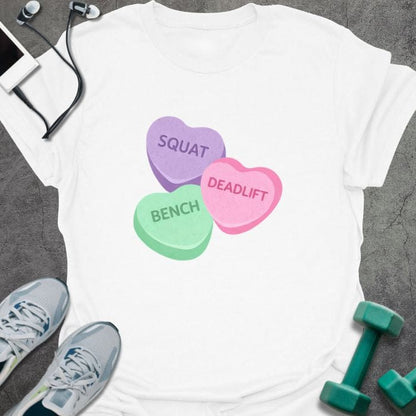 White t-shirt printed with "Squat Bench Deadlift" in purple, green, pink, with three conversation candy hearts in purple, green, and pink