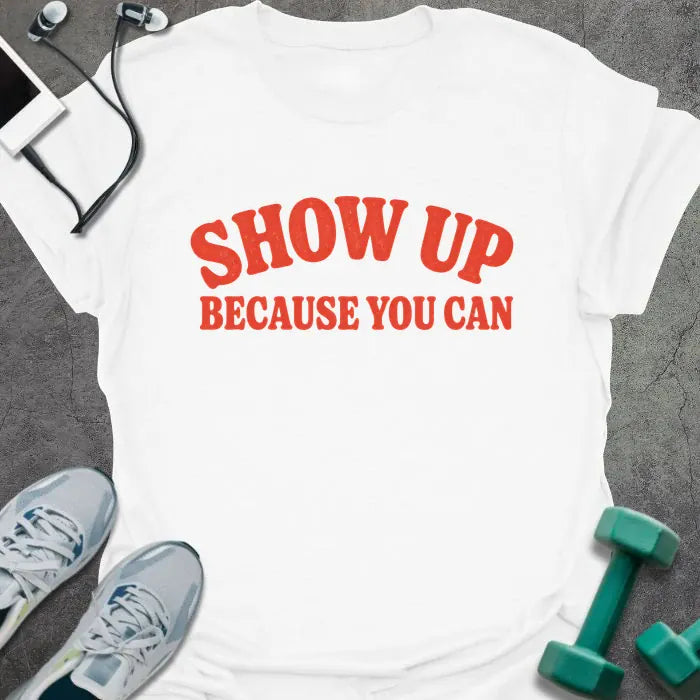White t-shirt printed with "SHOW UP BECAUSE YOU CAN" in red bold text