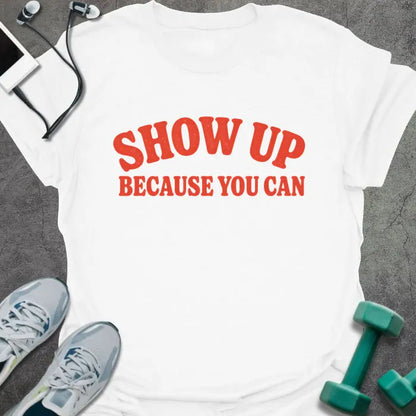 White t-shirt printed with "SHOW UP BECAUSE YOU CAN" in red bold text