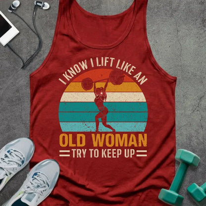 Red tank top printed with "I Know I Lift Like an Old Woman Try to Keep Up" in white, orange, and teal, with silhouette and sunset stripes