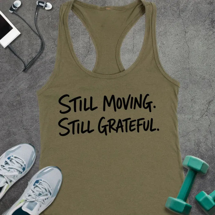 Military Green tank top printed with "STILL MOVING. STILL GRATEFUL." in black handwritten lettering